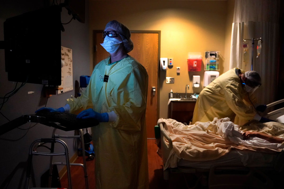 Surgeon in a dark hospital room watching a monitoring device.