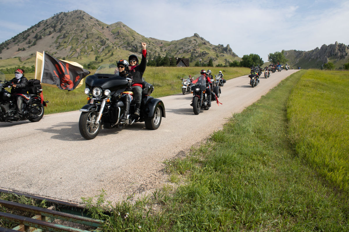 Prairie Rose Seminole, a citizen of the Three Affiliated Tribes, raises her fist as she rides out of Bear Butte during the 2023 Medicine Wheel Ride. 